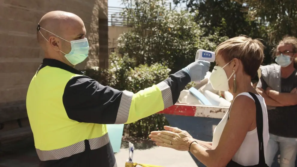 Un sanitario le toma la temperatura a una persona en el dispositivo para realizar PCR aleatorias para detectar asintomáticos de Covid-19 en la Comunidad de Madrid, en el barrio de Puente de Vallecas