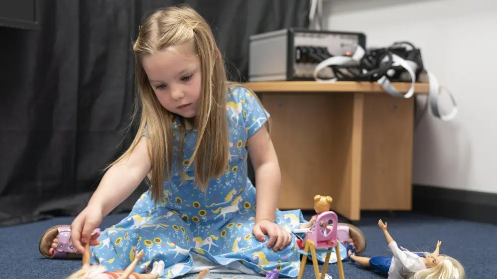 Una niña juega con varias muñecas.