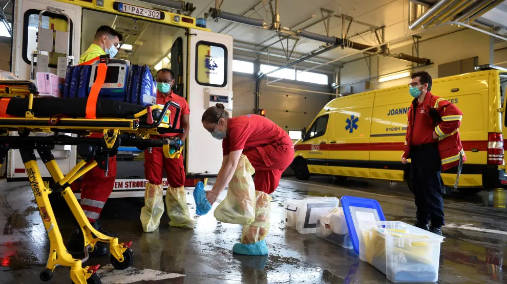 Varios sanitarios se ponen el traje de protección antes de subir a una ambulancia, en Ottignies, Bélgica.