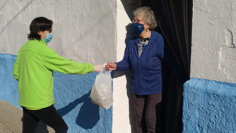 Angelines le lleva la comida a su casa a un usuario del centro de Villamayor.