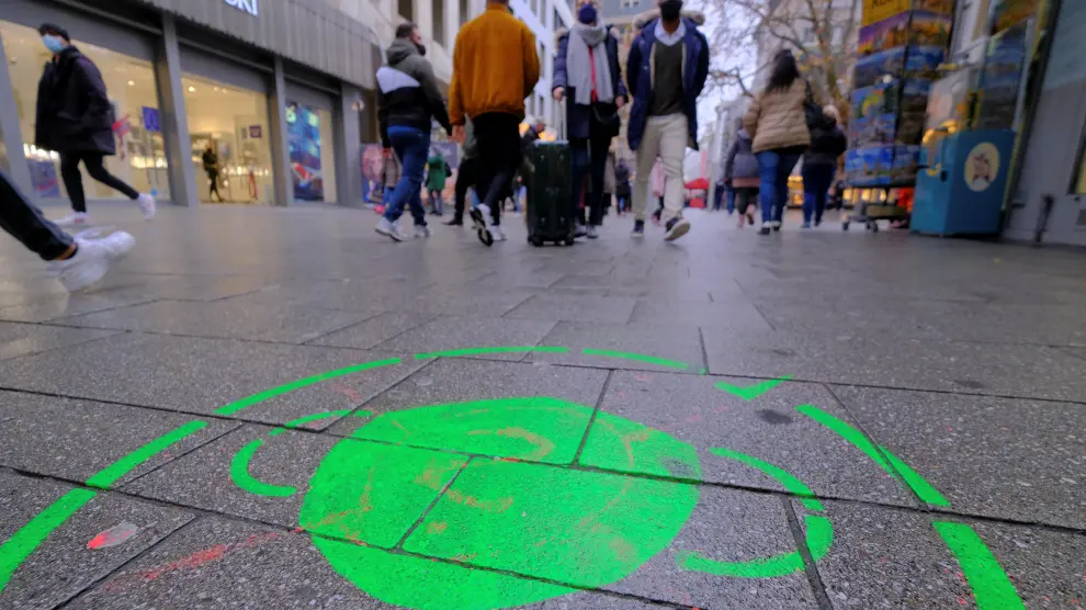 Un dibujo en el suelo recuerda la obligación de llevar mascarilla en una calle comercial de Colonia, Alemania.
