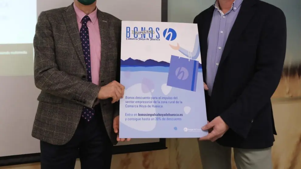 Salvador Cored, director general de la CEOS, y Sergio Moreu, consejero de Desarrollo de la Comarca Hoya de Huesca, con el cartel de la campaña.