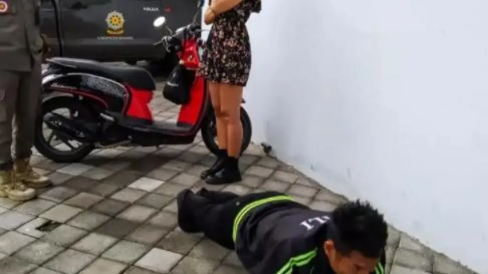 Una persona hace flexiones en una calle de Bali ante un policía por no llevar mascarilla.