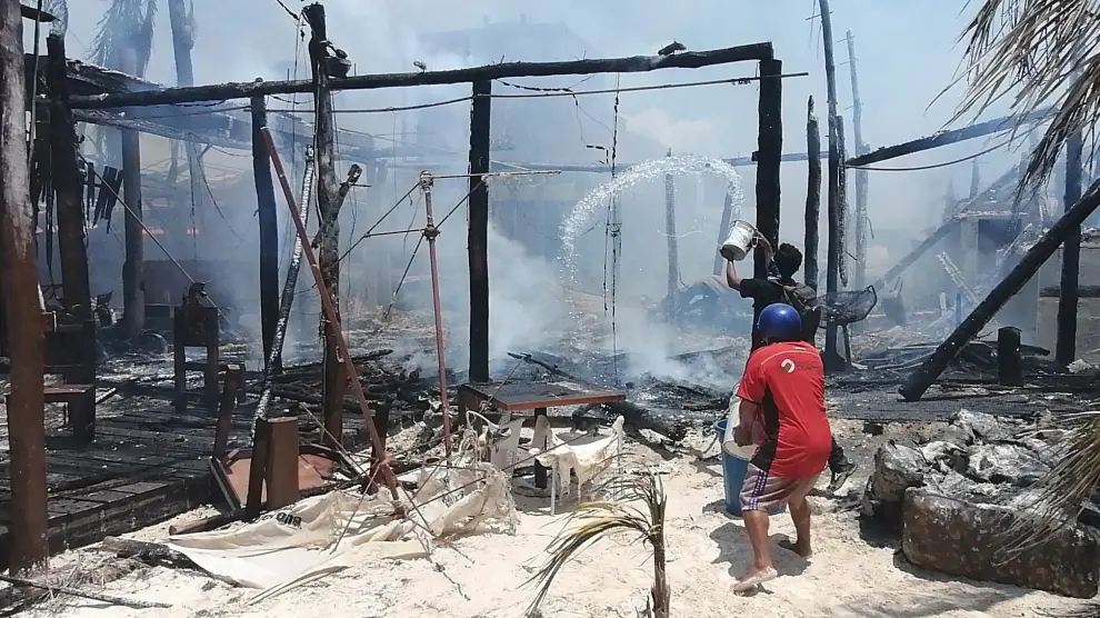 Turistas y vendedores intentan controlar un incendio con cubetas de agua del mar