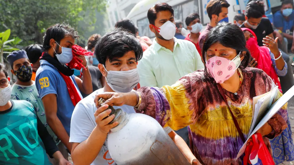 Una mujer y su hijo portan una bombona de oxígeno para recargarla en Nueva Delhi.