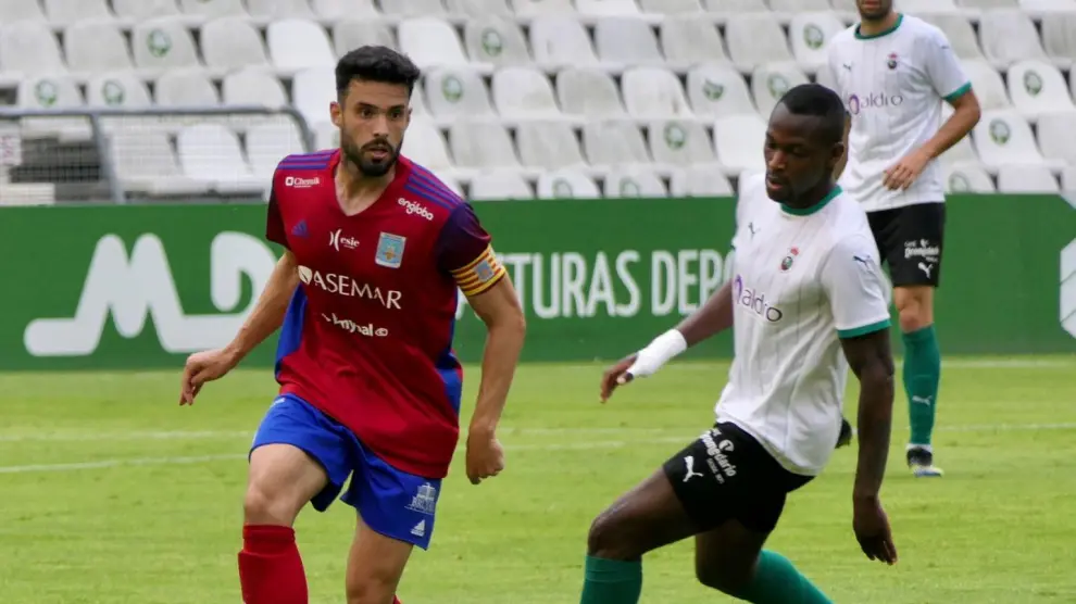 Santigosa conduce el balón ante la presión de un jugador del Racing de Santander.