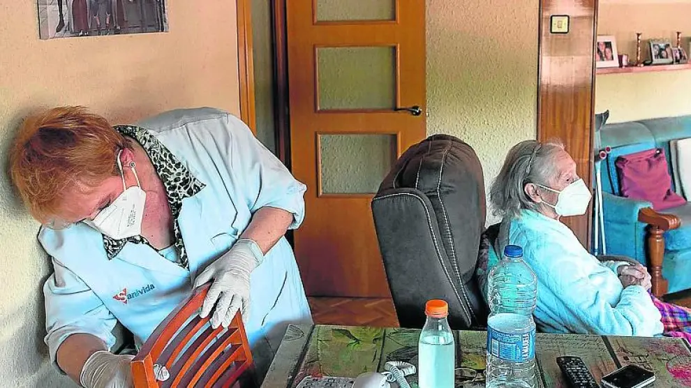 Celia Álvarez, de 89 años, en su vivienda de Zaragoza junto a una de las trabajadoras del SAD.