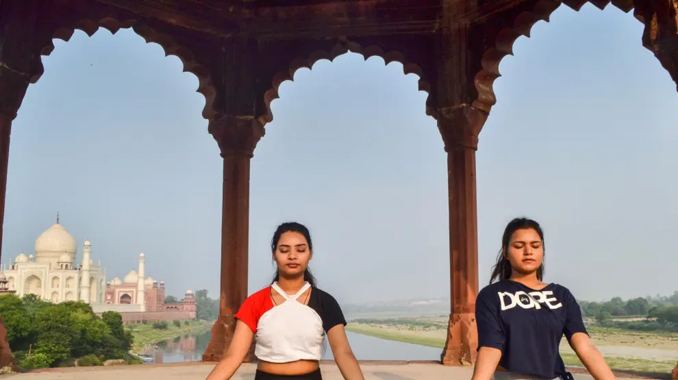 Dos mujeres practican yoga cerca del Taj Mahal, en la India.