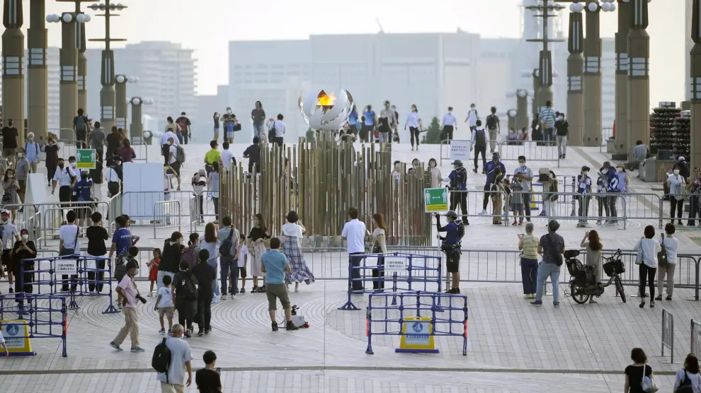 Gente alrededor de la llama olímpica en Tokio.
