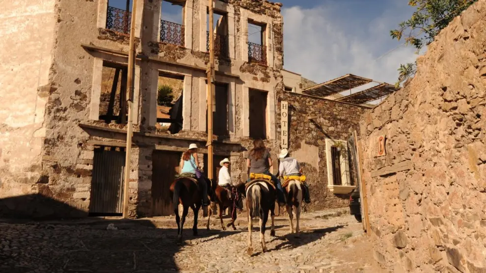 Turistas a caballo pasan por un antiguo hotel