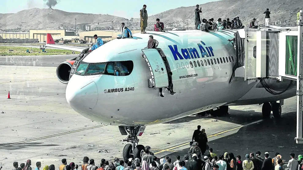 Decenas de personas esperan subidas a un avión y en la pista para intentar huir del país.