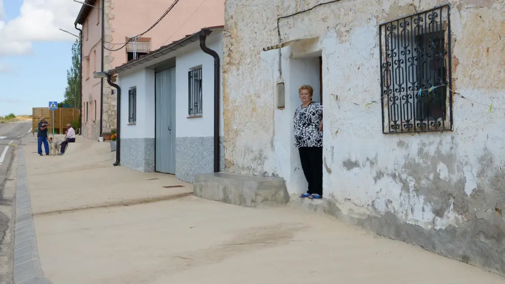 Una vecina se asoma a la puerta de su casa en Allueva, donde deben recorrer 40 kilómetros para llegar a un supermercado.