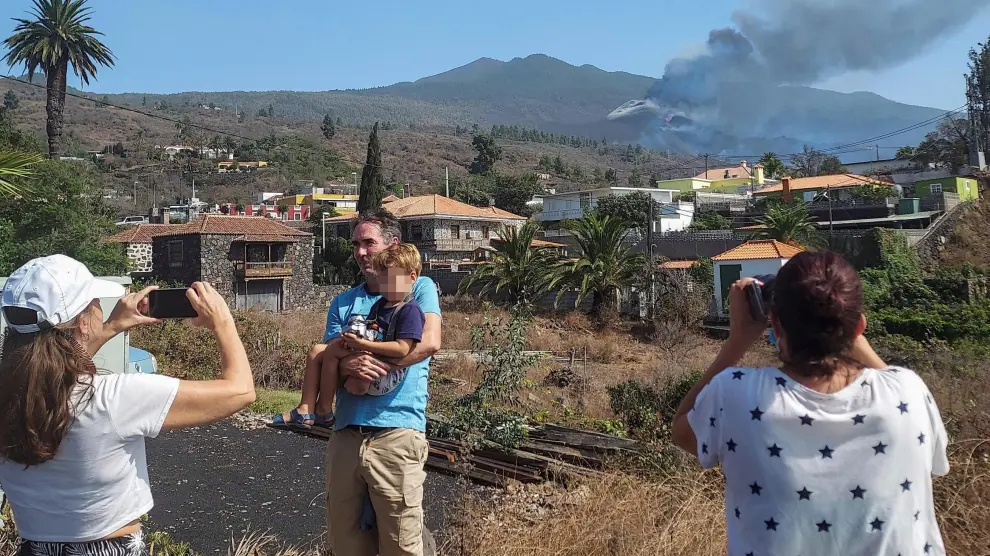 Algunos turistas, haciéndose fotos en La Palma con el volcán al fondo.