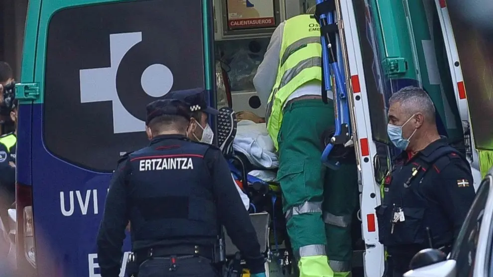 Agentes de la Ertzaintza acompañan a la ambulancia al hombre que se había atrincherado dentro del bar La Parada de Baracaldo.