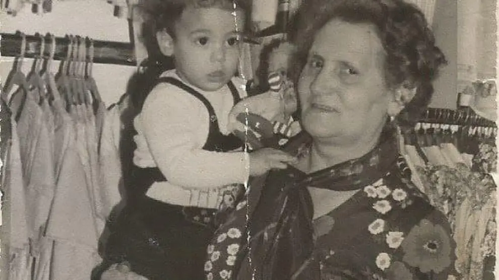 Elena Martín, con un nieto en brazos, en la tienda que fundó en 1969.