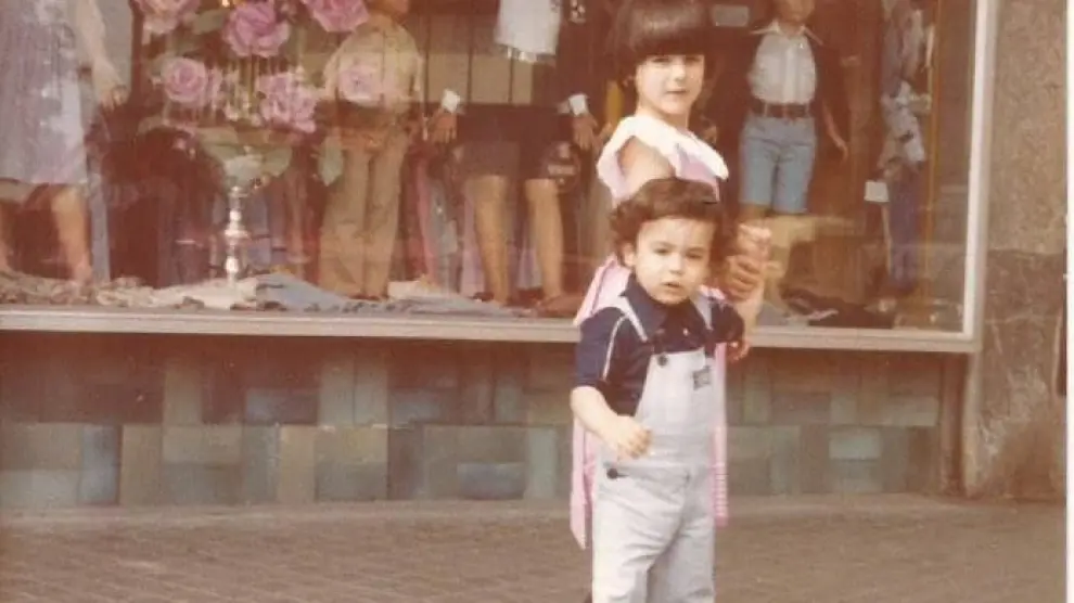 Elena Guía, de pequeña, con su hermano junto al escaparate de la tienda.