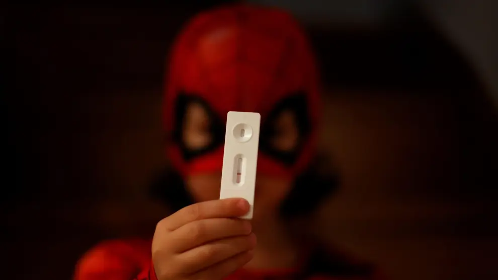 Un niño vestido de Spiderman muestra el resultado de un test de antígenos.