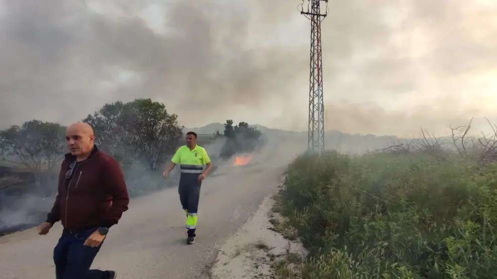 Dos vecinos de El Burgo de Ebro, pasan apresurados junto a las llamas