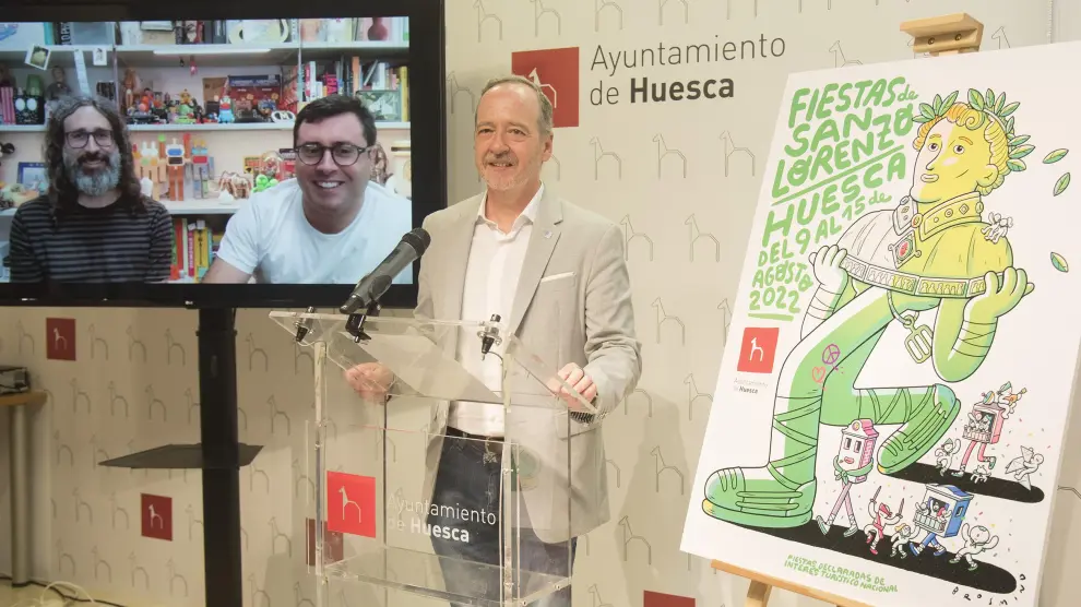 El concejal de Fiestas, Ramón Lasaosa, junto a cartel de San Lorenzo 2022. En la pantalla, Juan y Alejandro Mingarro.