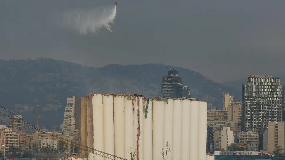 Un helicóptero vierte agua sobre los silos del puerto de Beirut.