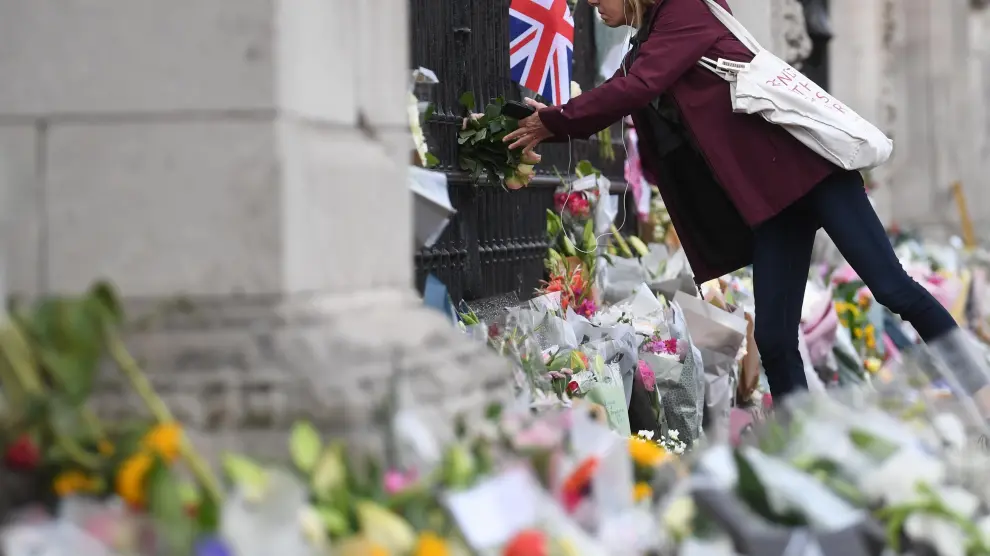 Una persona deja flores a las puertas del Buckingham Palace tras el fallecimiento de Isabel II.