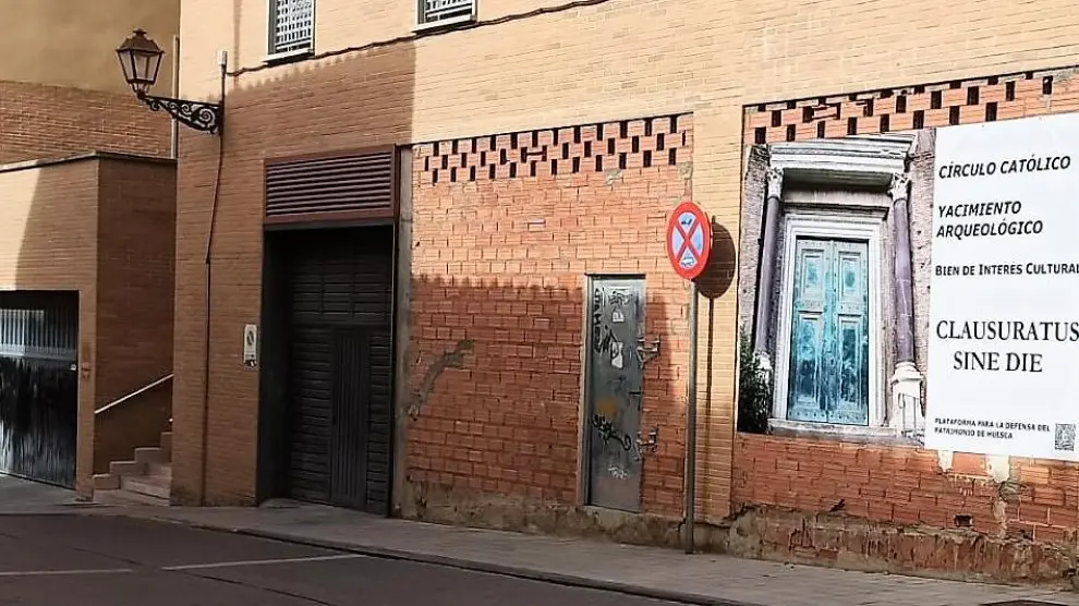 La Plataforma para la Defensa del Patrimonio de Huesca ha colocado una lona en la fachada del garaje por el que se accede a los restos del Círculo Católico