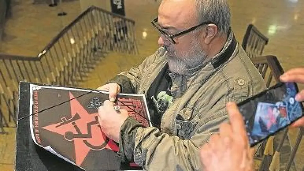 Álex de la Iglesia, este lunes, firmando un póster de su filme 'Acción mutante' en la escaleras de los cines Palafox de Zaragoza.