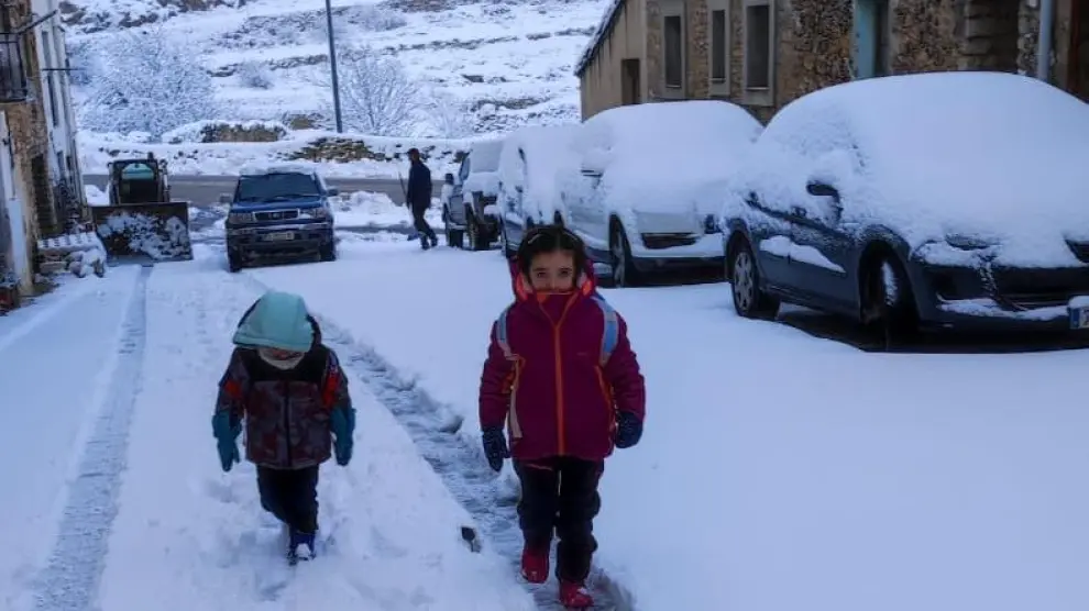Dos niños se dirigen al colegio en Mosqueruela en medio de la nevada,