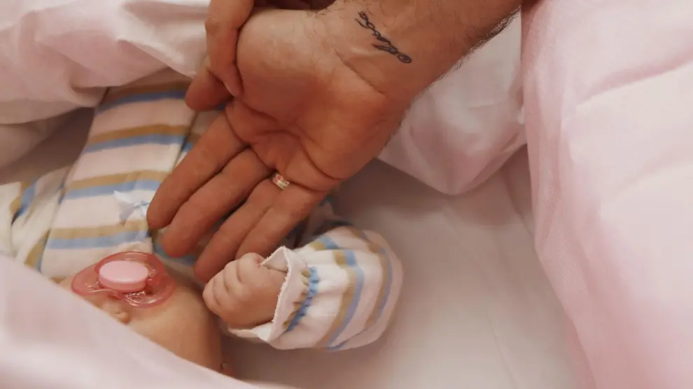 Un bebé, nacido con técnicas de fertilización artificial, sujeta el dedo de su madre.
