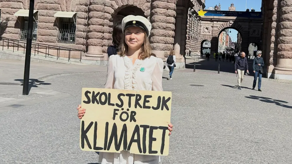 Greta Thunberg con un cartel que dice "Huelga escolar por el clima".
