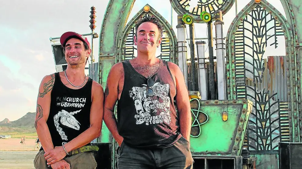 Los ingleses Justin y Josh, dos participantes, con la cabina de un dj inspirada en una iglesia gótica.