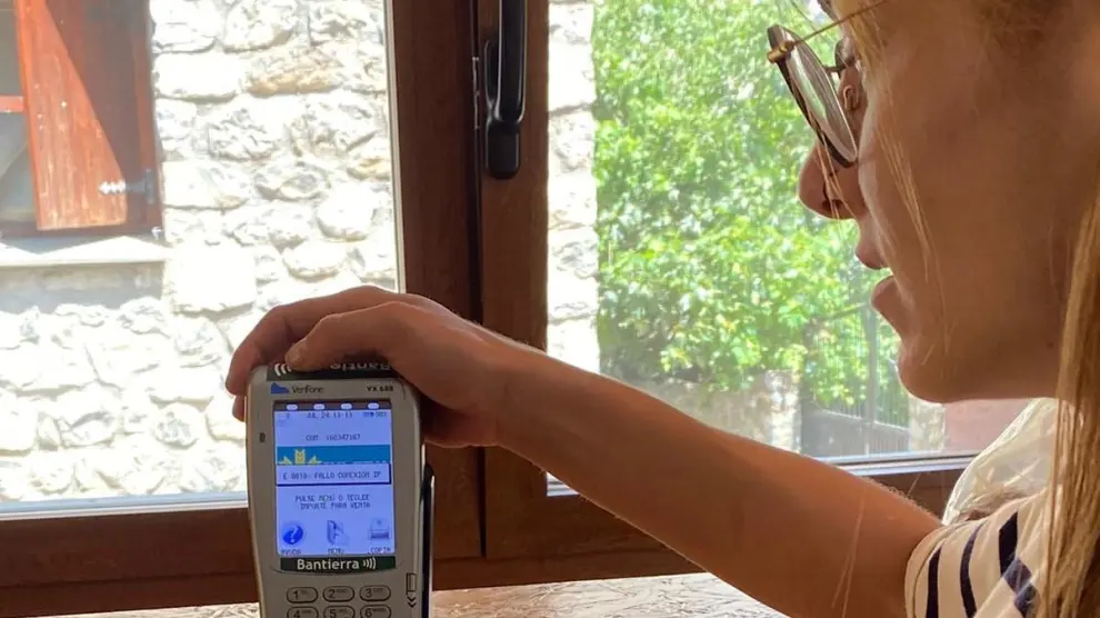 Una empresaria de Saravillo muestra su datáfono con el mensaje recurrente de 'fallo de conexión'.