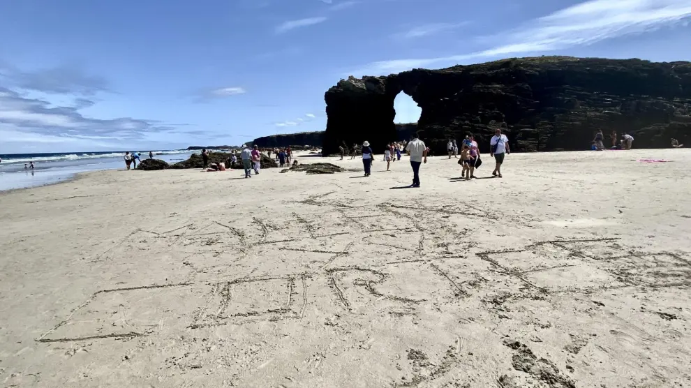 Los nombres de dos pueblos aragoneses escritos en la arena de la playa de las Catedrales, en Lugo.