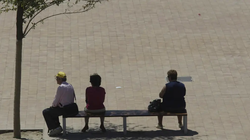 Tres ciudadanos, en uno de los escasos bancos con algo de sombra de Ranillas.