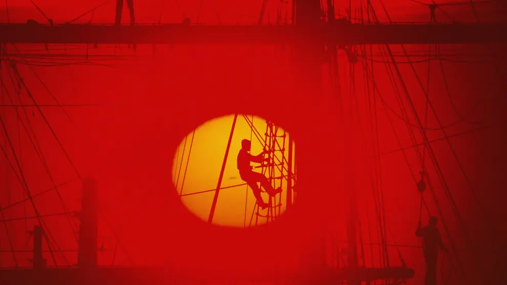Un marinero trepa por la jarcia de un barco al caer el sol en Buenos Aires.
