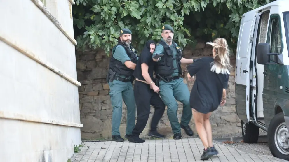 El detenido, saliendo de los juzgados de Boltaña esposado por la Guardia Civil en dirección a la cárcel de Zuera. Una joven ha conseguido saltarse el cordón policial para increpar al presunto asesino de Úrbez.