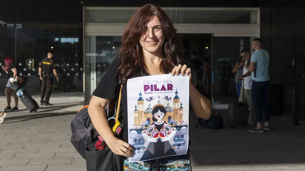 María Iglesias sostiene en la estación de Delicias el cartel que diseñó, a su llegada ayer a Zaragoza desde Barcelona. La barbastrense todavía no había podido celebrar este año las Fiestas del Pilar.