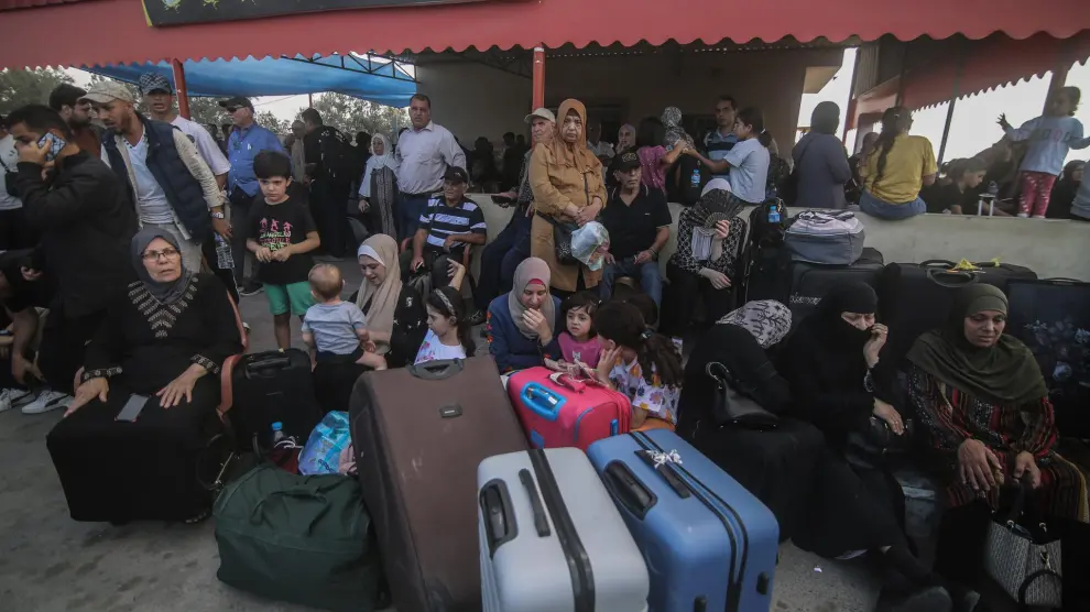 Un grupo de civiles palestinos espera en Rafah para cruzar la frontera entre la Franja de Gaza y Egipto