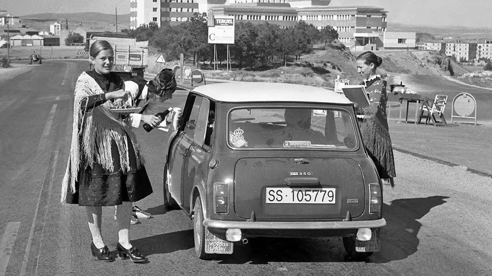 Varios jóvenes agasajan a un turista con jamón y vino a la entrada de Teruel, en una foto de la década de 1970.
