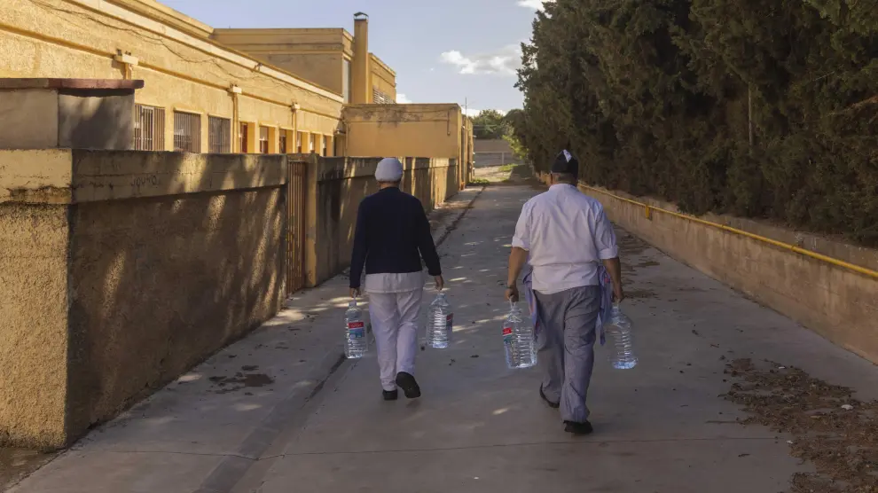 El equipo de cocina del colegio Moncayo de Tarazona vuelve al centro tras rellenar las garrafas de agua en el depósito que la DGA ha instalado en el patio del centro.