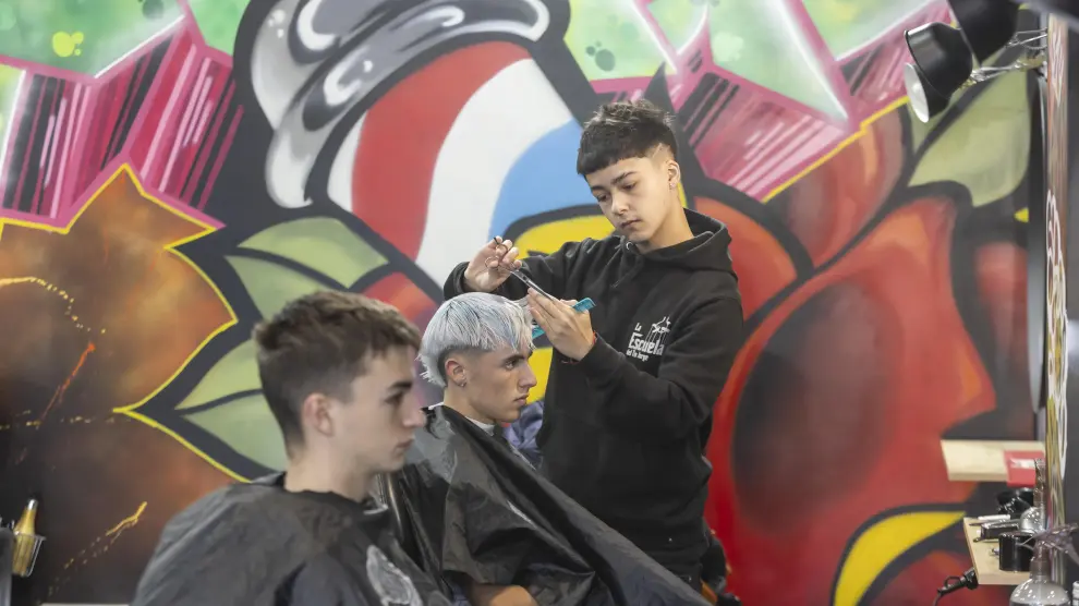 Uno de los alumnos corta el pelo a un cliente en la Escuela del Tío Jorge, este lunes en Zaragoza.