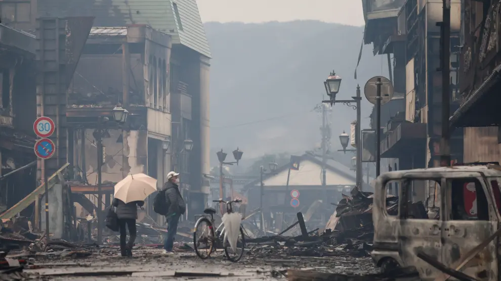 Un hombre camina por una calle de Wajima con edificios caídos, en la prefectura de Ishikawa.