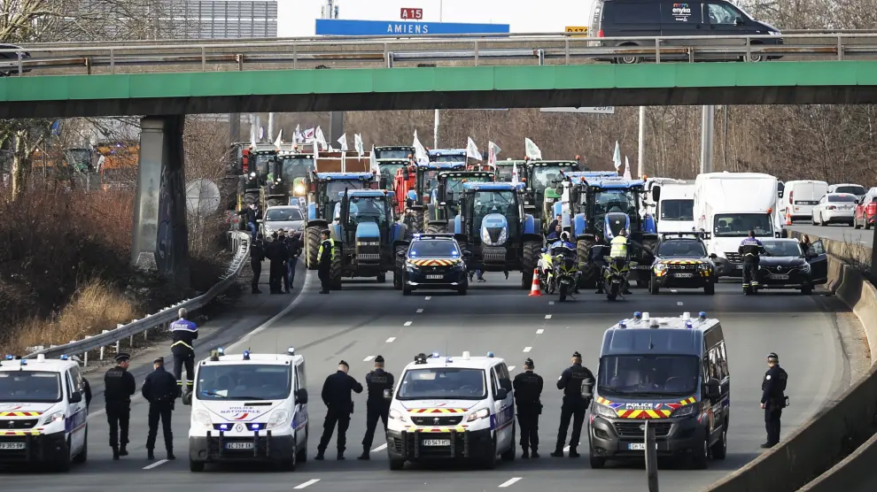 Agentes de policía vigilan decenas de tractores que participan en una manifestación en la autopista A15 cerca de Argenteuil, al norte de París