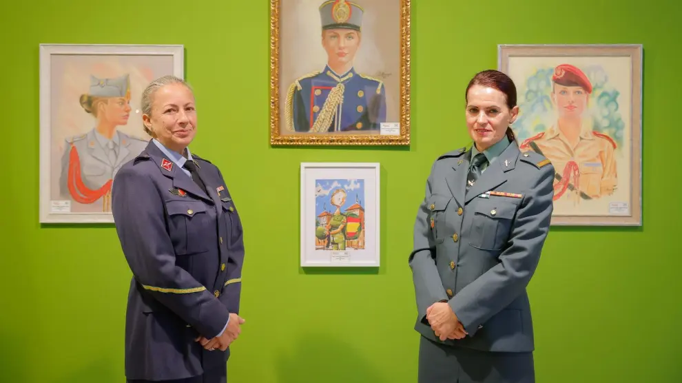 Las cabos Mónica Rodríguez Suárez, del Ejército del Aire (a la izquierda), y María Carmen Carbajal Fernández, de la Guardia Civil, ante unos cuadros de la princesa Leonor en la exposición de la legada de la mujer a las Fuerzas Armadas hace 35 años.