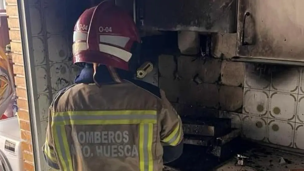 Un bombero realizando tareas de extinción de un incendio en la cocina de una vivienda de Huesca.