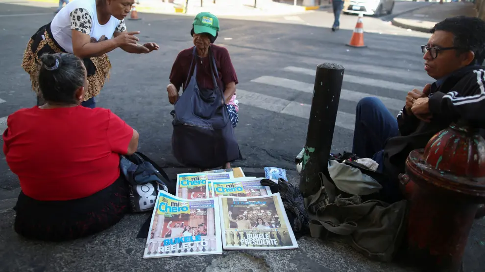 La gente habla mientras un hombre vende periódicos después de las elecciones presidenciales, en San Salvador