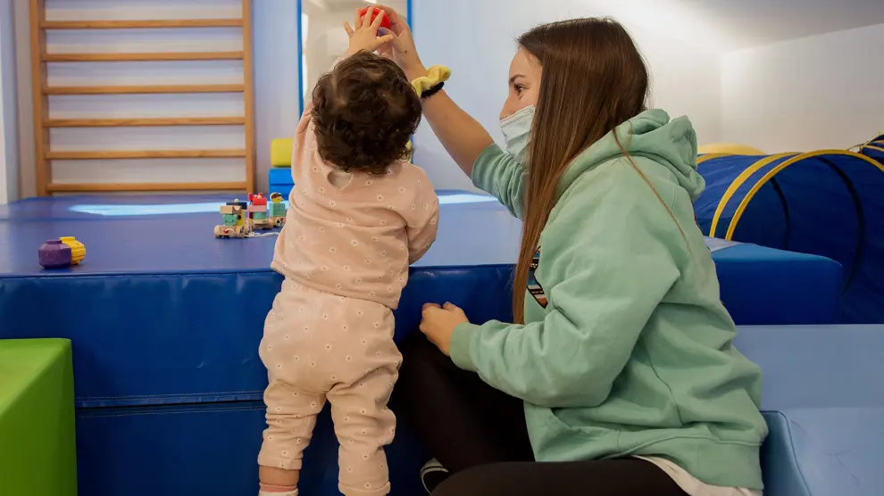 Una fisioterapeuta en una sesión de estimulación precoz y ejercicios con una niña en La Almunia de Doña Godina