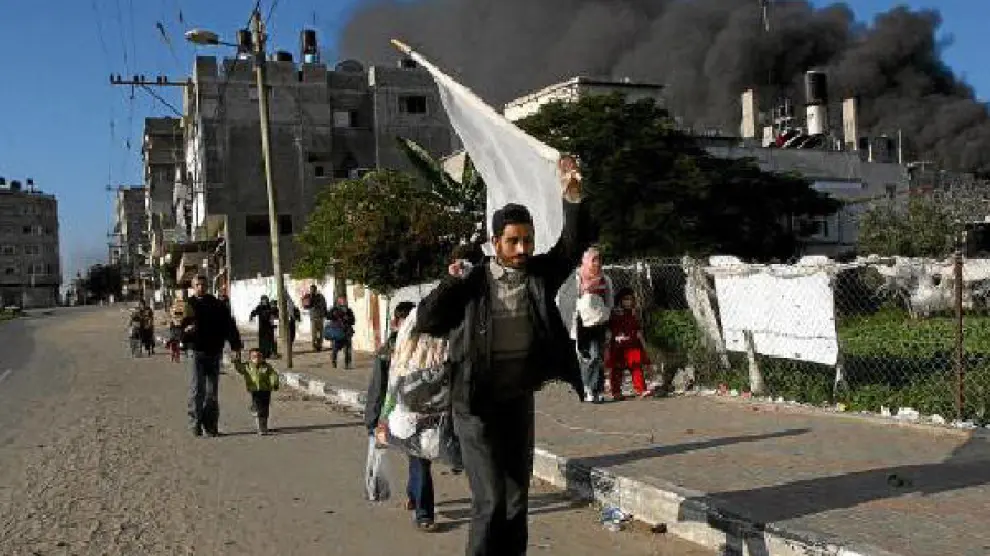 Un palestino sujeta una bandera blanca al abandonar su casa en la franja de Gaza.