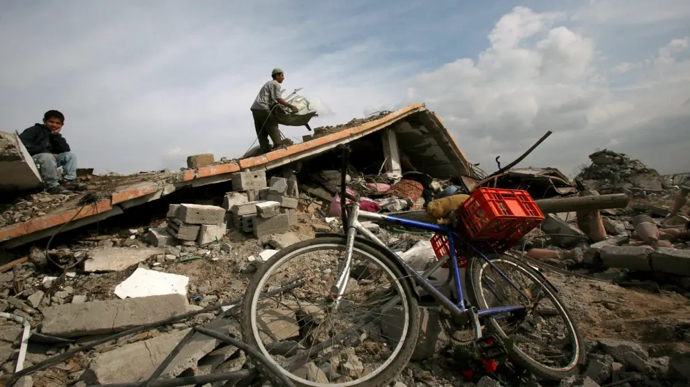 Varias personas, entre los escombros de la que fuera su vivienda, destruída durante la ofensiva israelí