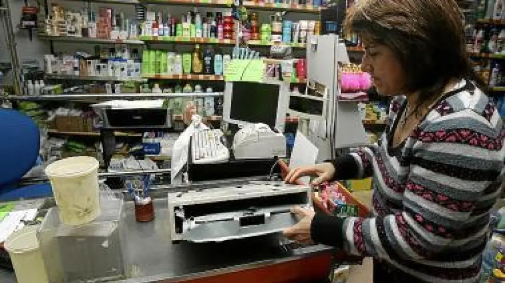 Isabel Alegre muestra la caja registradora de la tienda reventada.
